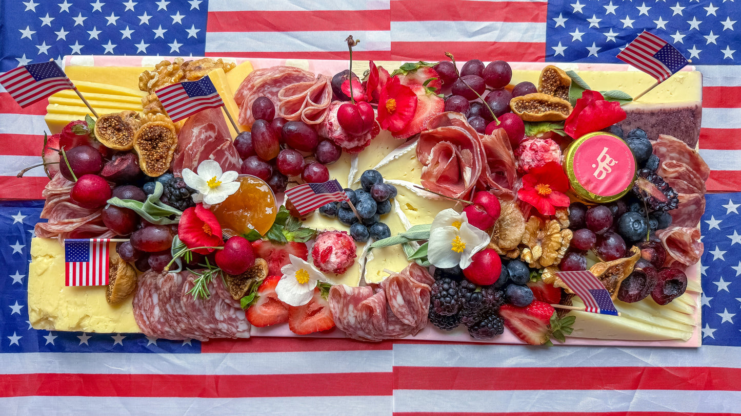 Platter of assorted meats, cheeses, and fruits on an American flag background